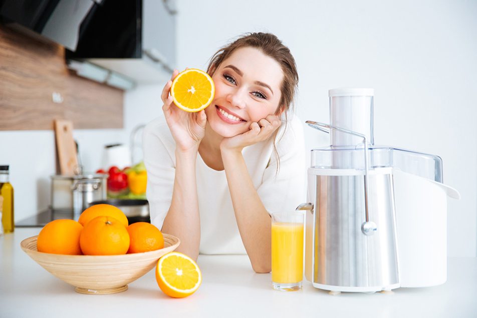 Dona in una cucina domestica che si nutre di acido ascorbico, ovvero vitamina C, attraverso una spremuta di arancia fatta in casa