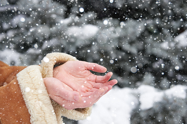 Donna all’aria aperta che raccoglie la neve durante la stagione invernale, a rischio di osservare mani secche