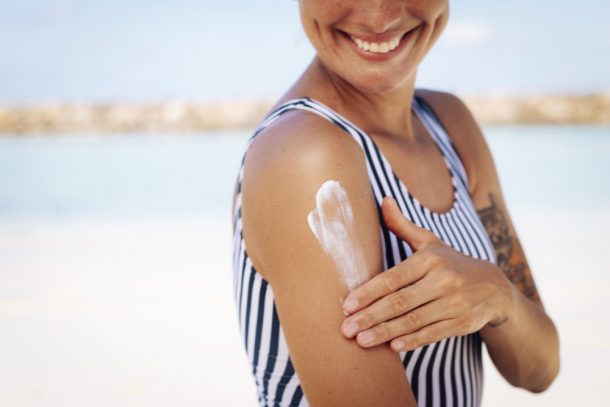 Donna al mare si spalma la crema per proteggere la pelle e prevenire melanoma benigno