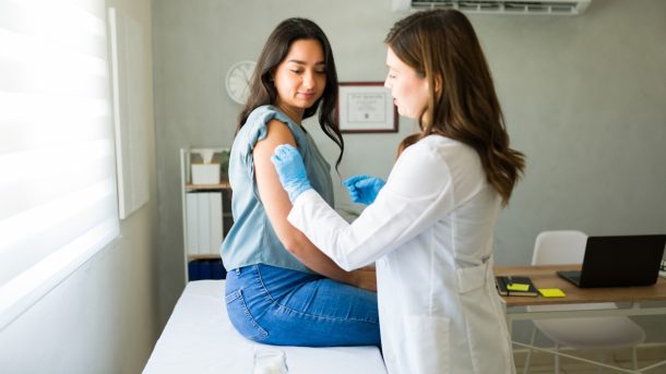 giovane-donna-facendo-vaccino-antinfluenzale Giovane donna dal suo medico mentre si prepara a ricevere il vaccino antinfluenzale