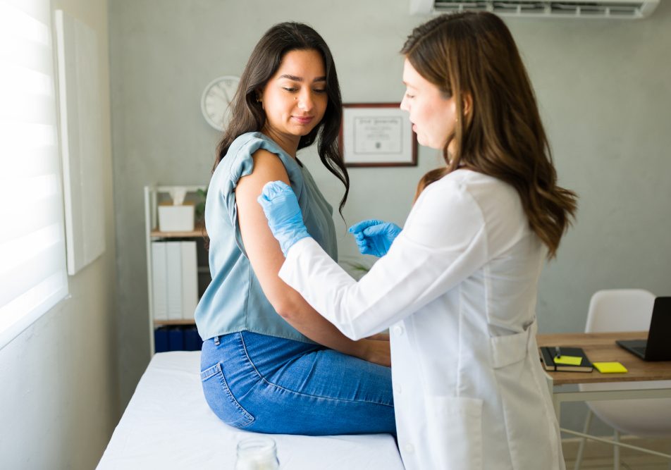 giovane-donna-facendo-vaccino-antinfluenzale Giovane donna dal suo medico mentre si prepara a ricevere il vaccino antinfluenzale