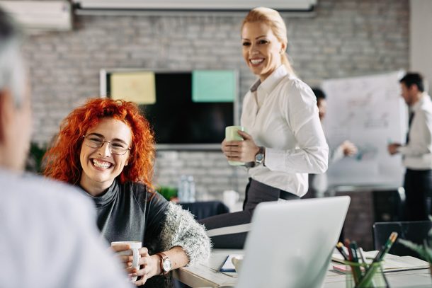 Giovane impiegata che si svaga in compagnia del collega durante una pausa caffè per calibrare il suo work-life balance