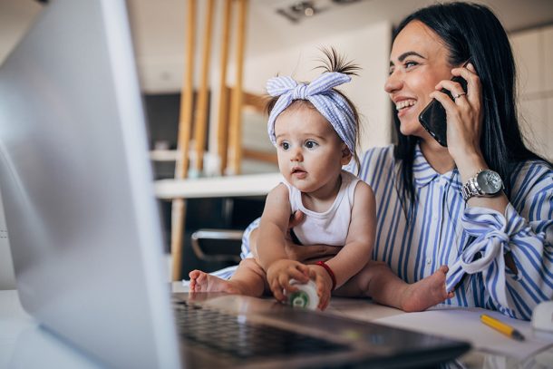 Mamma e bambina che lavorano assieme alla scrivania lavanti al PC; il genitore è al telefono per domandare informazioni sul bonus mamme lavoratrici