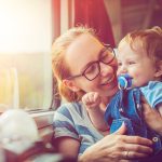 Mamma che viaggia serenamente con il suo bambino in treno, essendo informata su come togliergli il ciuccio senza provocare stress