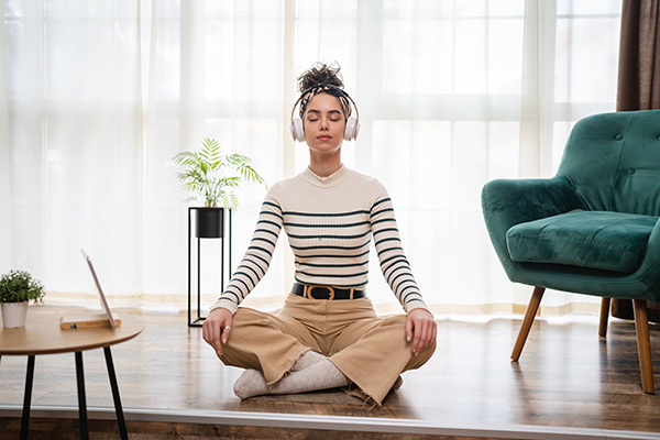 Ragazza a casa che indossa un paio di cuffie e segue una meditazione guidata per la gestione dell’ansia