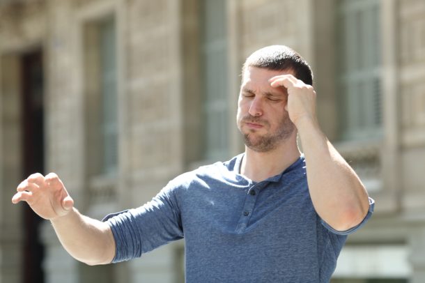 Uomo che, mentre cammina per la strada, avverte ansia e giramenti di testa