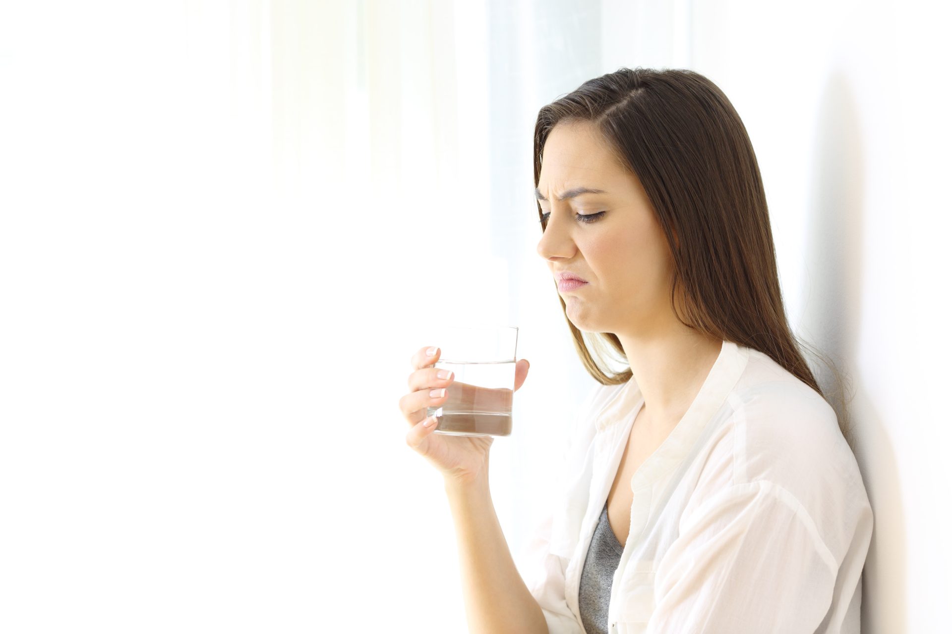 donna con nausea tiene in mano bicchiere d'acqua