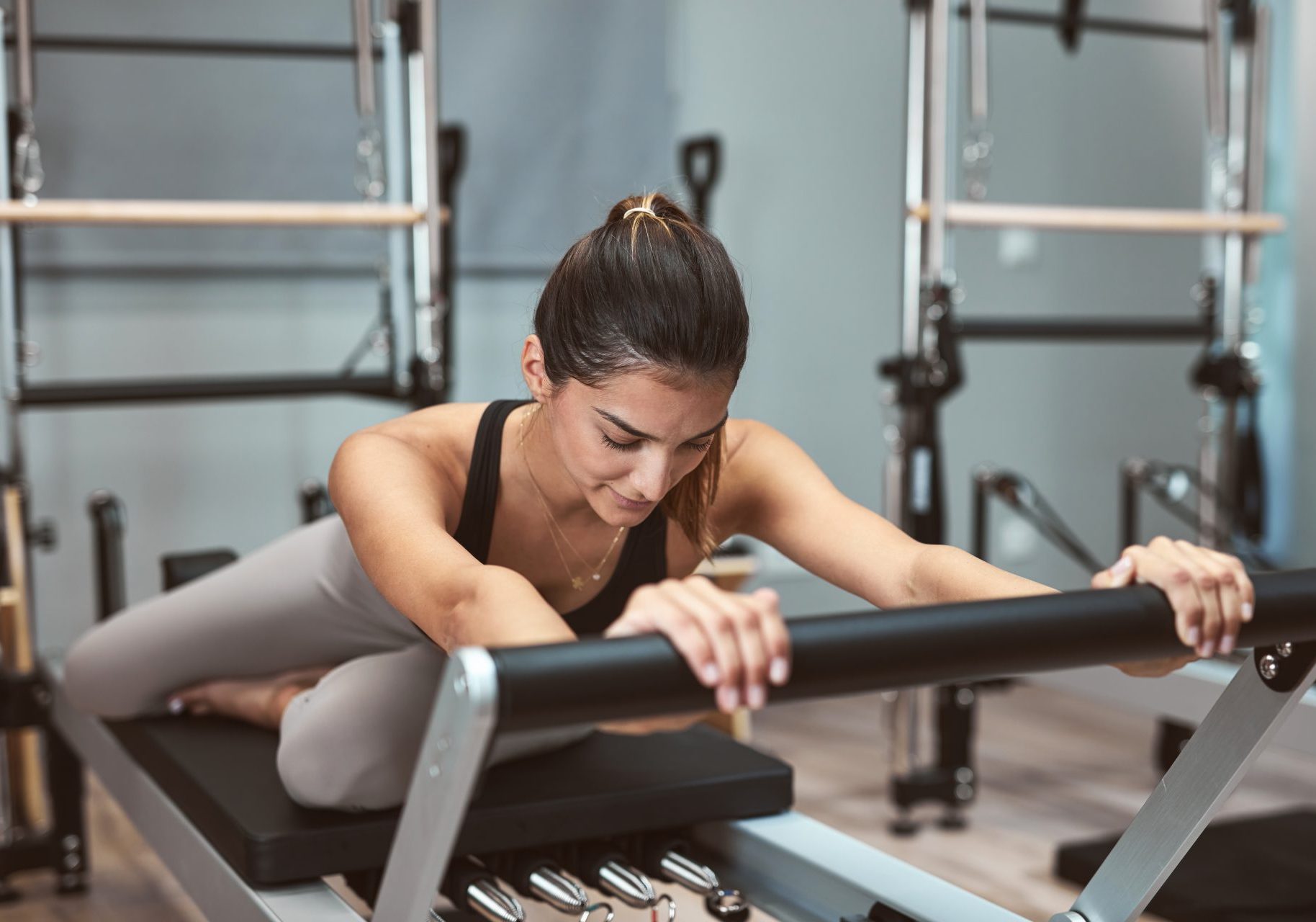pilates-reformer_cover giovane donna esegue esercizio di pilates reformer