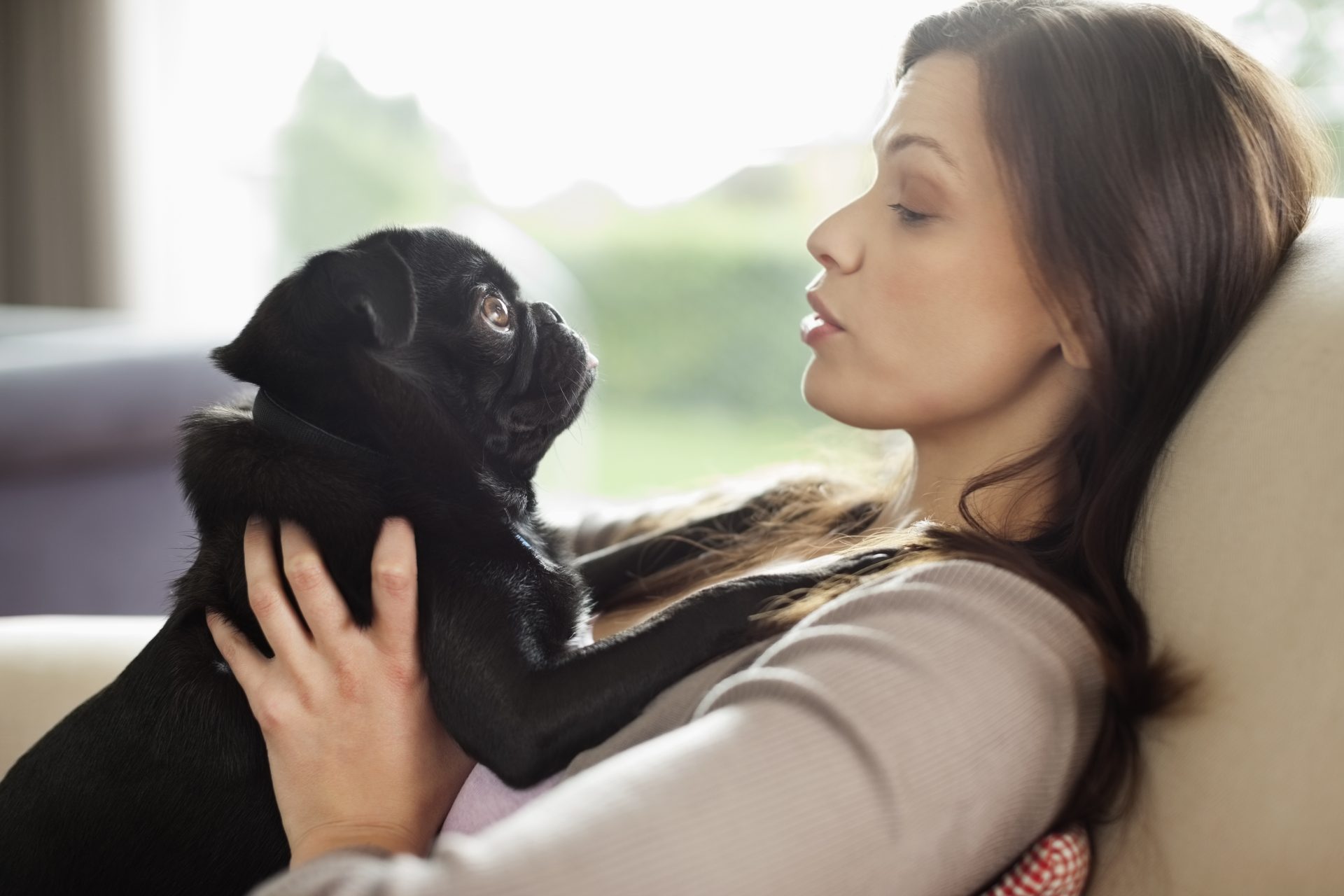 donna sdraiata sul divano con cane in braccio