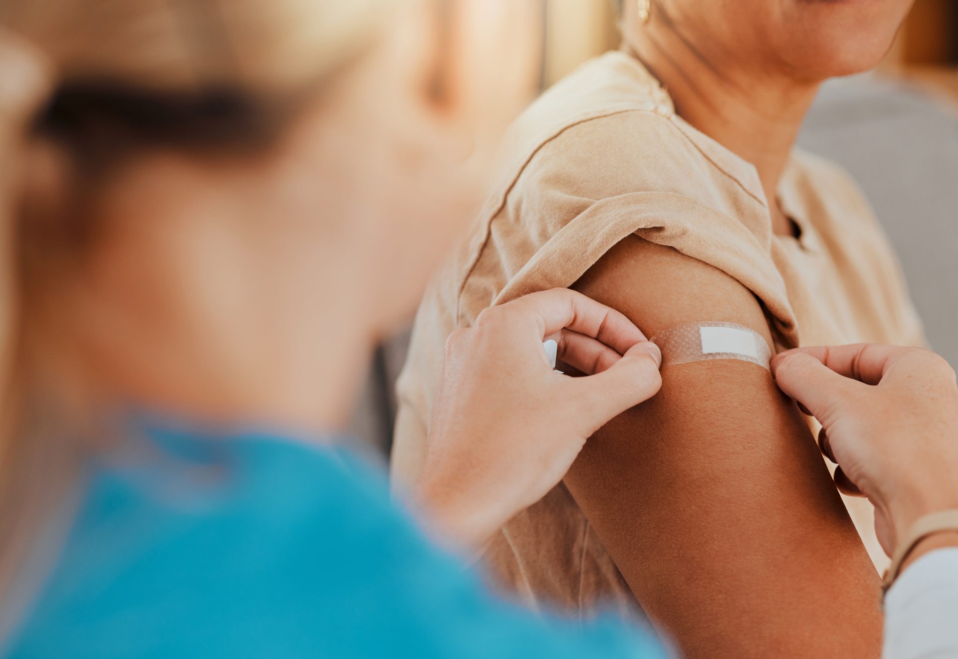 infermiera applica cerotto sulla spalla di una paziente dopo la vaccinazione