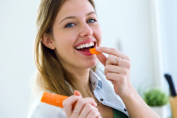 donna sorridente che mangia una carota