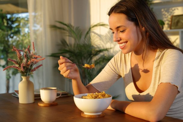 giovane donna sorridente mangia cereali al mattino