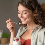 giovane donna sorridente mangia yogurt