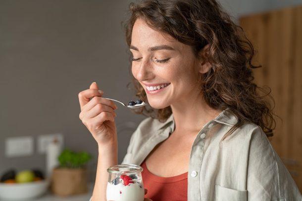 giovane donna sorridente mangia yogurt