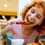 ragazza dai capelli rossi mangia spiedino di pollo