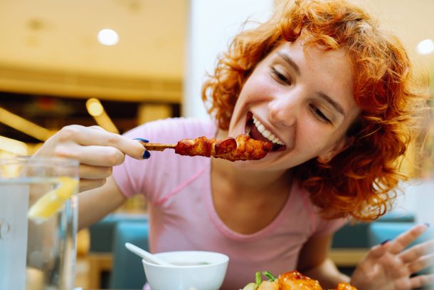 ragazza dai capelli rossi mangia spiedino di pollo