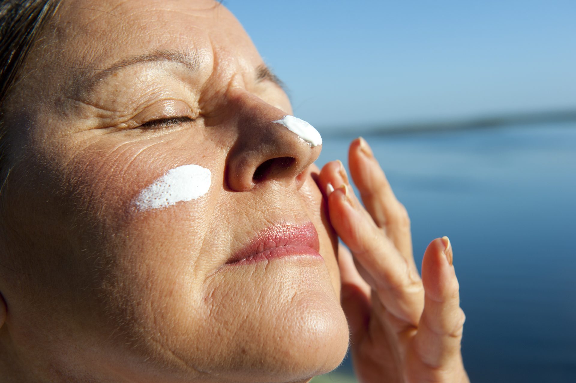 donna spalma crema solare sul viso