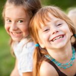 due bambine sorridenti con capelli lunghi biondi