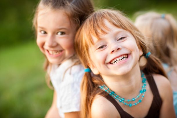 due bambine sorridenti con capelli lunghi biondi