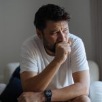 uomo seduto in poltrona tossisce
