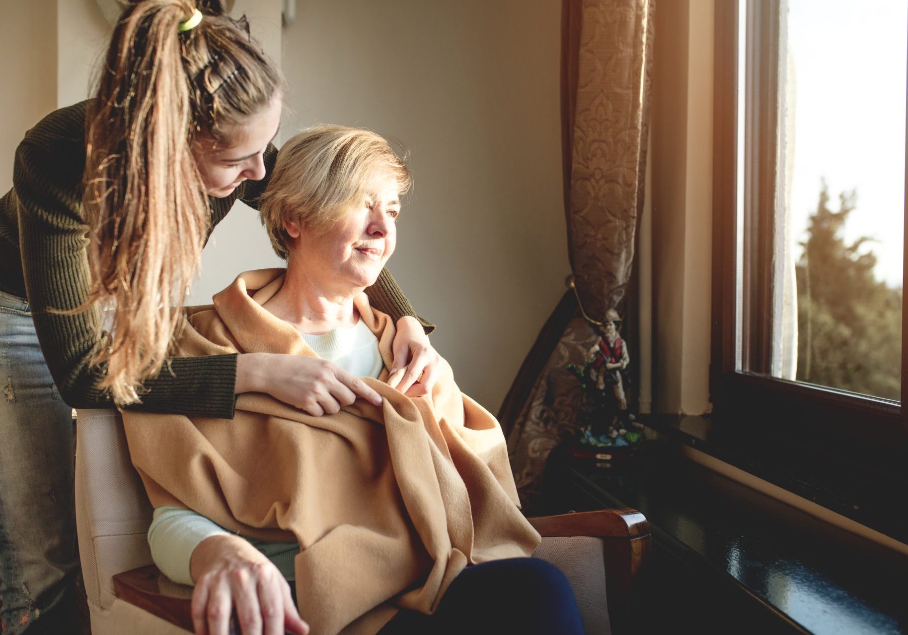 caregiving-familiare_cover giovane donna copre le spalle di una donna seduta con una sciarpa