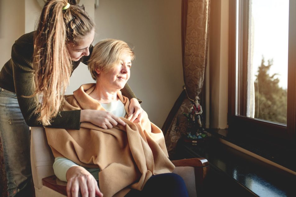 caregiving-familiare_cover giovane donna copre le spalle di una donna seduta con una sciarpa