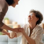 giovane donna caregiver sorridente tiene le mani di donna anziana