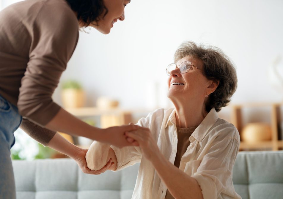 donne-caregiver_cover giovane donna caregiver sorridente tiene le mani di donna anziana