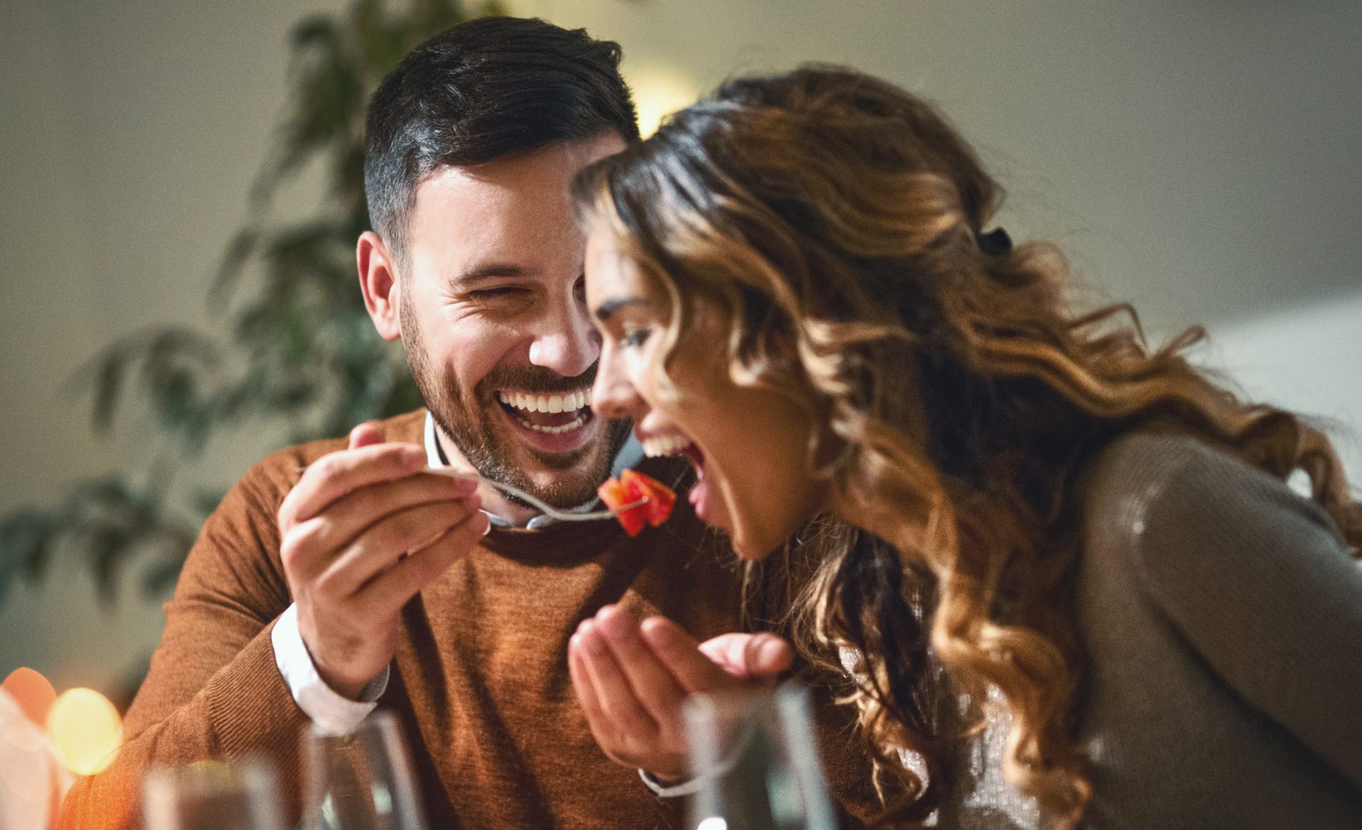 uomo sorridente porge forchetta con cibo a donna