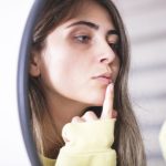 donna controlla herpes labiale allo specchio