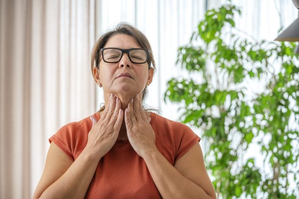 donna matura tocca il collo dolorante con entrambe le mani