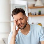 giovane uomo a casa con mal di testa