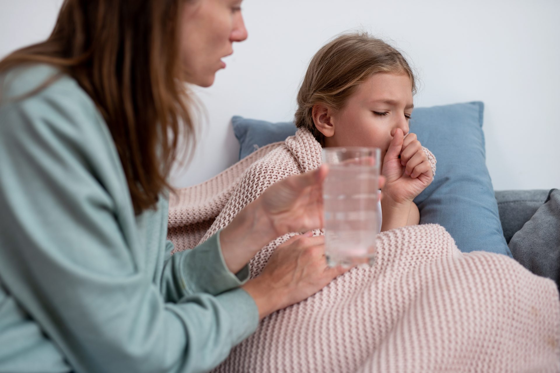 madre porge bicchiere d'acqua a figlia che tossisce