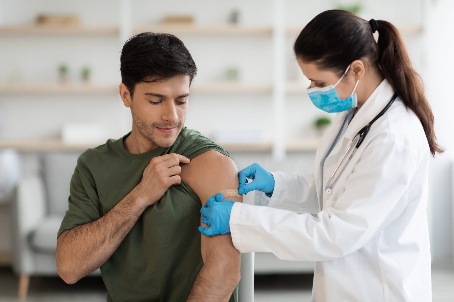 dottoressa mette cerotto sul braccio di giovane uomo dopo vaccinazione