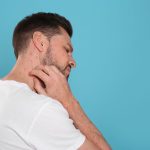 uomo si gratta il collo coperto da eruzioni cutanee