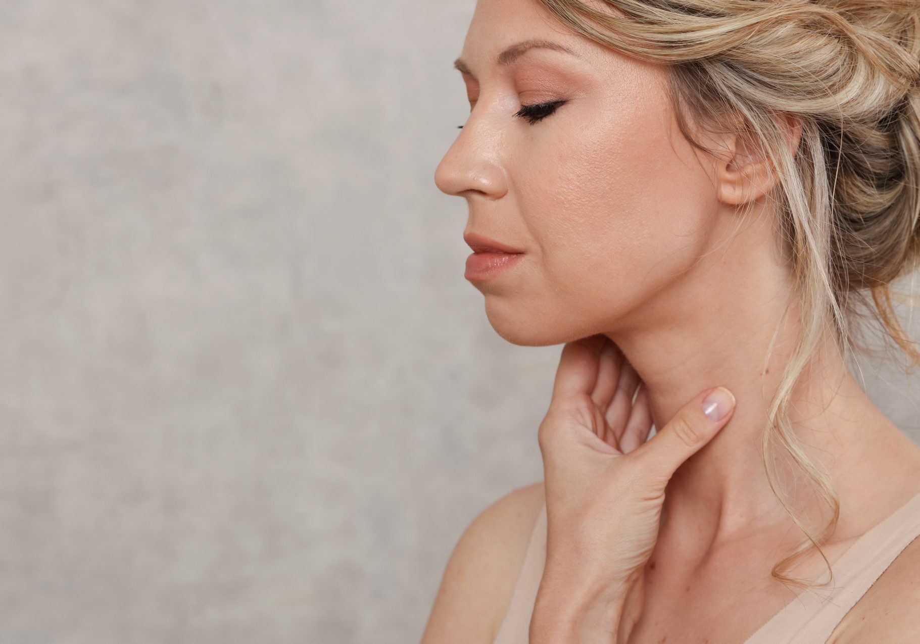 carcinoma-tiroideo_cover donna bionda si tocca il collo con una mano