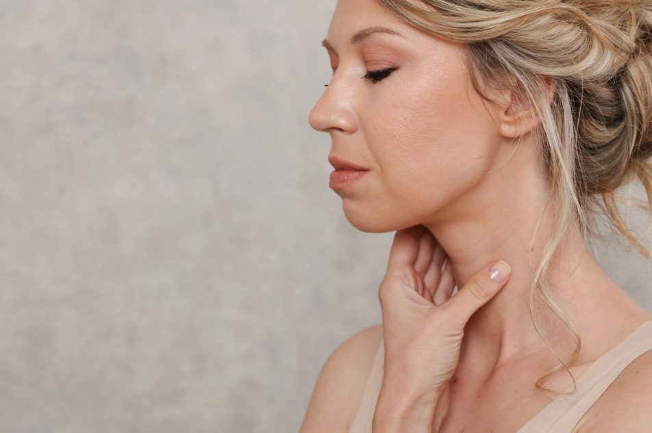 carcinoma-tiroideo_cover donna bionda si tocca il collo con una mano