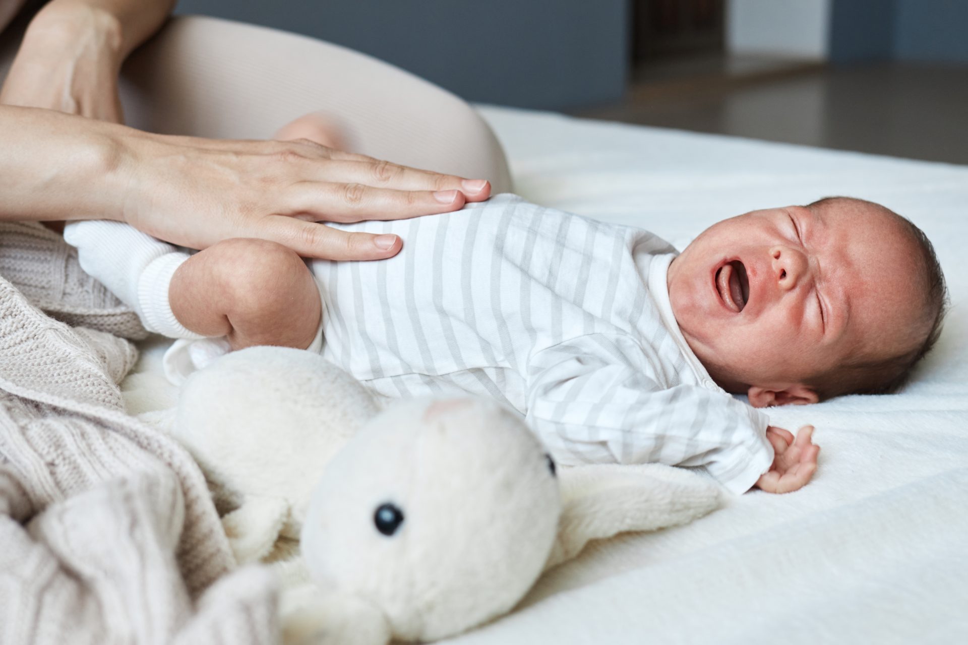 neonato piange disteso sul letto