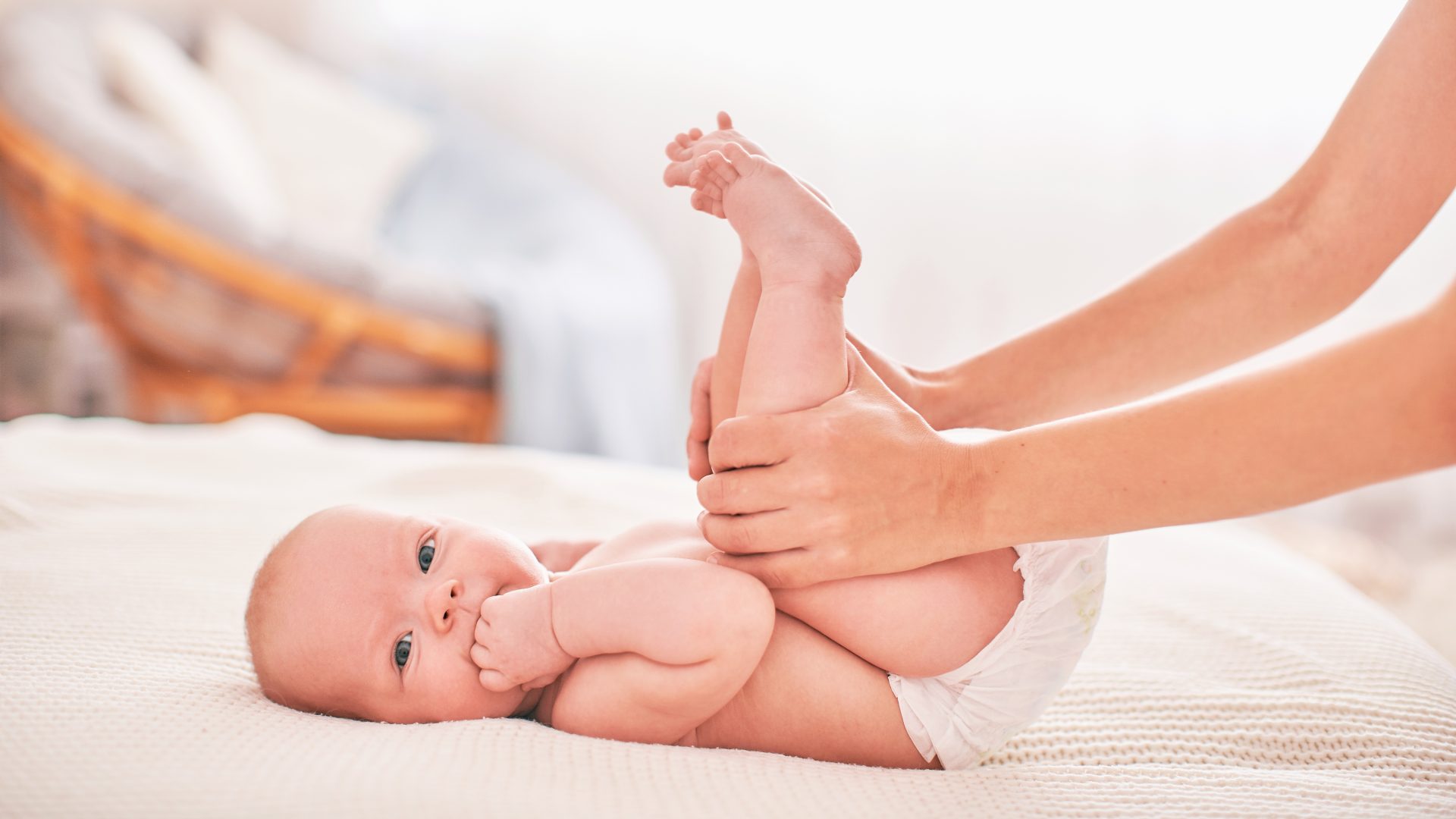 madre solleva le gambe del neonato verso l'addome
