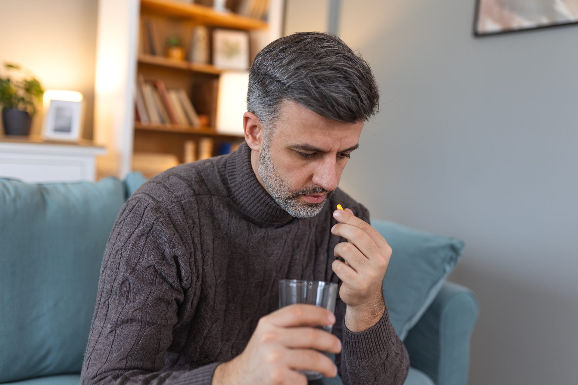 uomo prende pillola con bicchiere d'acqua