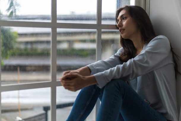 giovane donna triste alla finestra