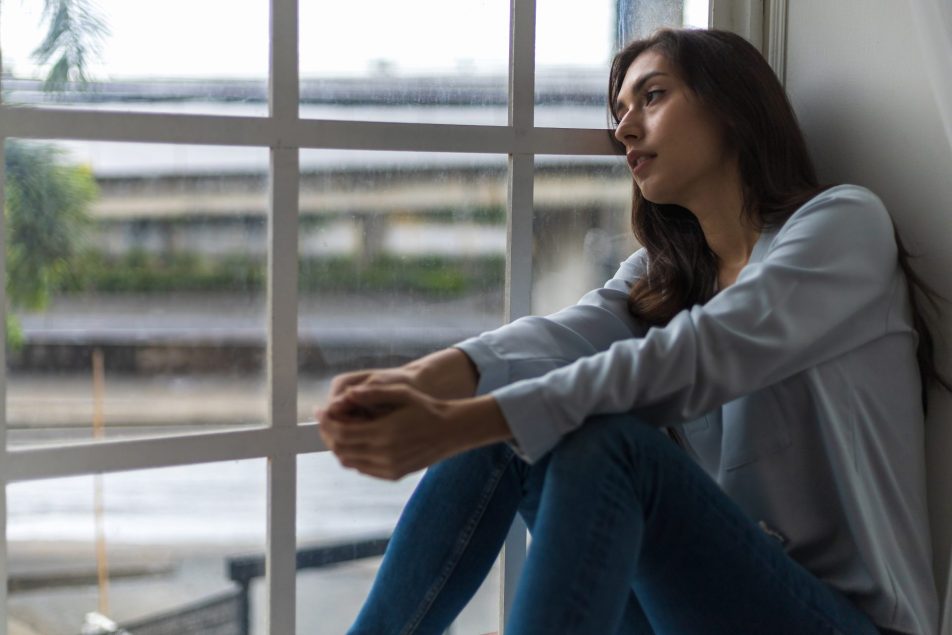 giovane donna triste alla finestra