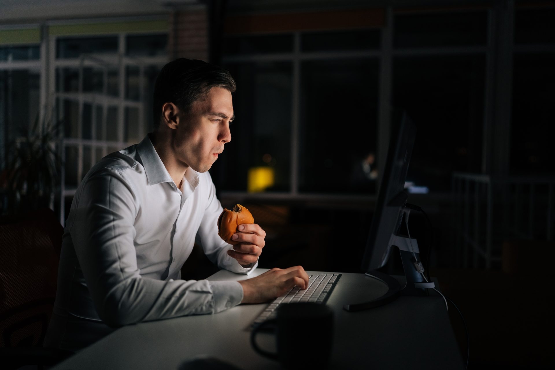 uomo mangia panino al computer
