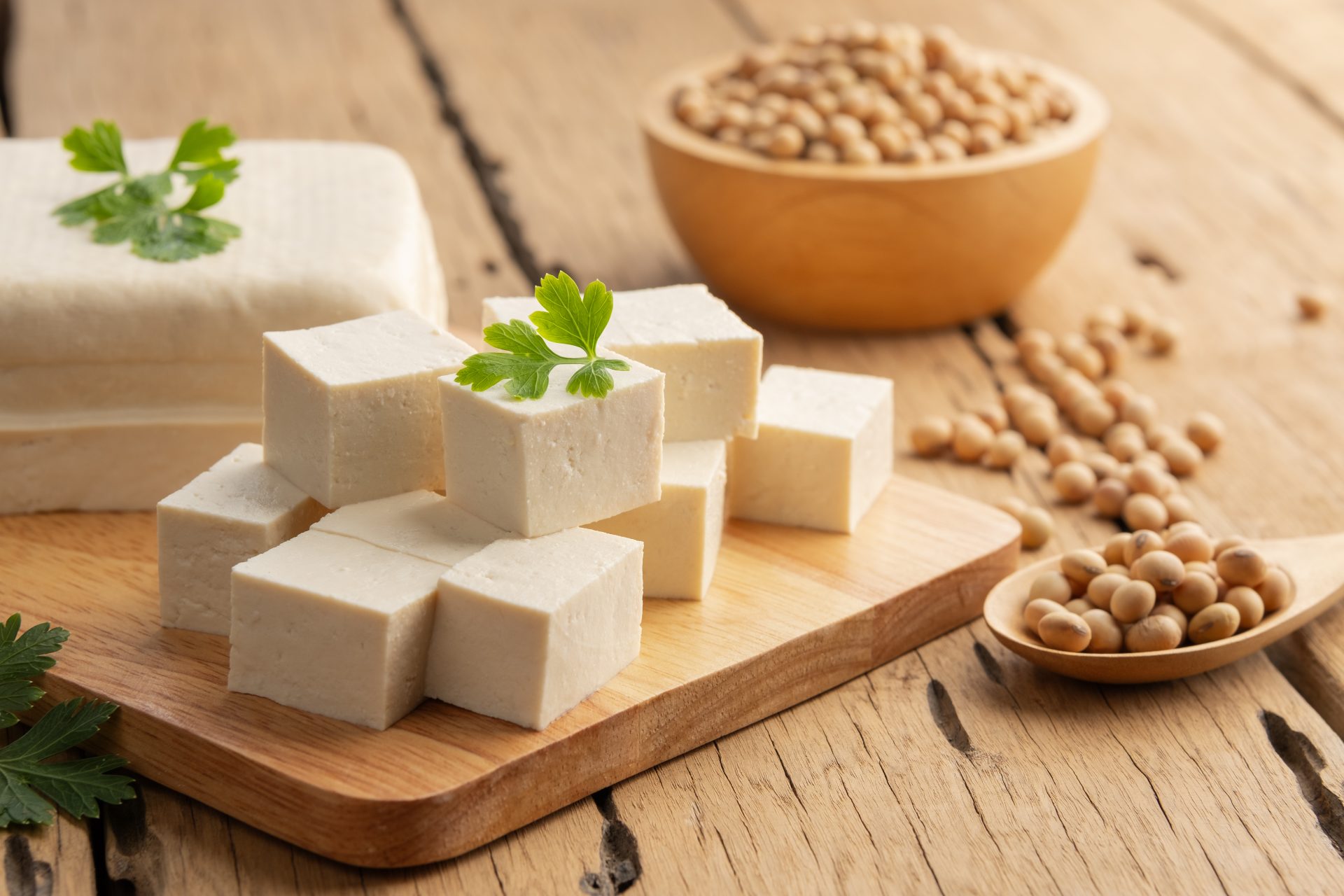 cubetti di tofu su un tagliere e ceci in un cucchiaio su un tavolo