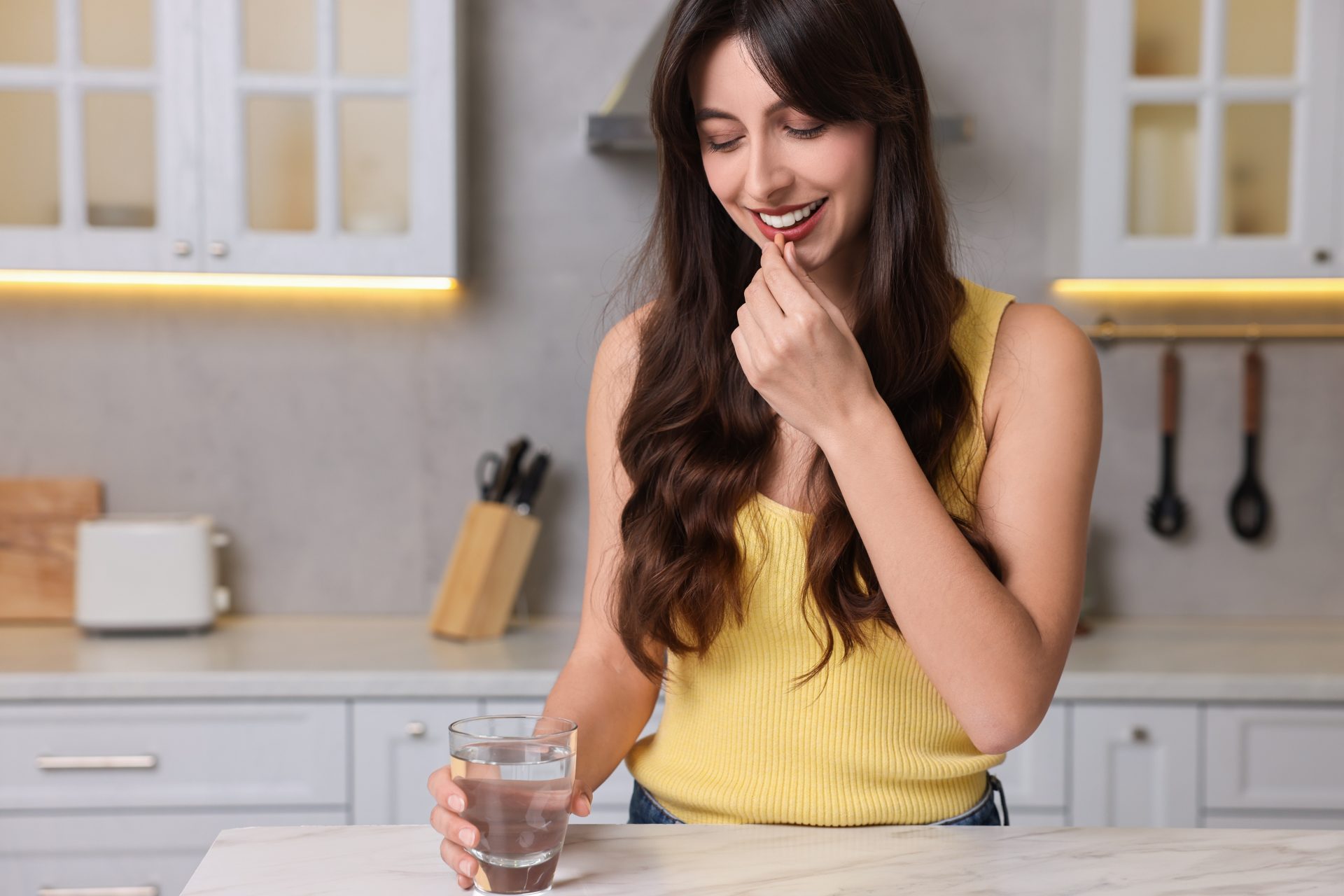 giovane donna assume integratore alimentare con bicchiere d'acqua