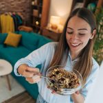 giovane donna mangia cereali da una ciotola