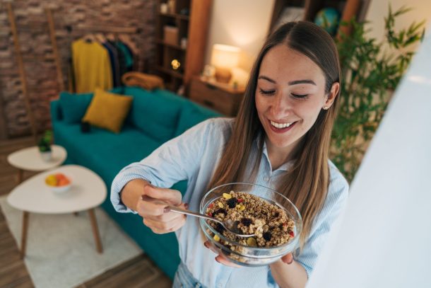 giovane donna mangia cereali da una ciotola
