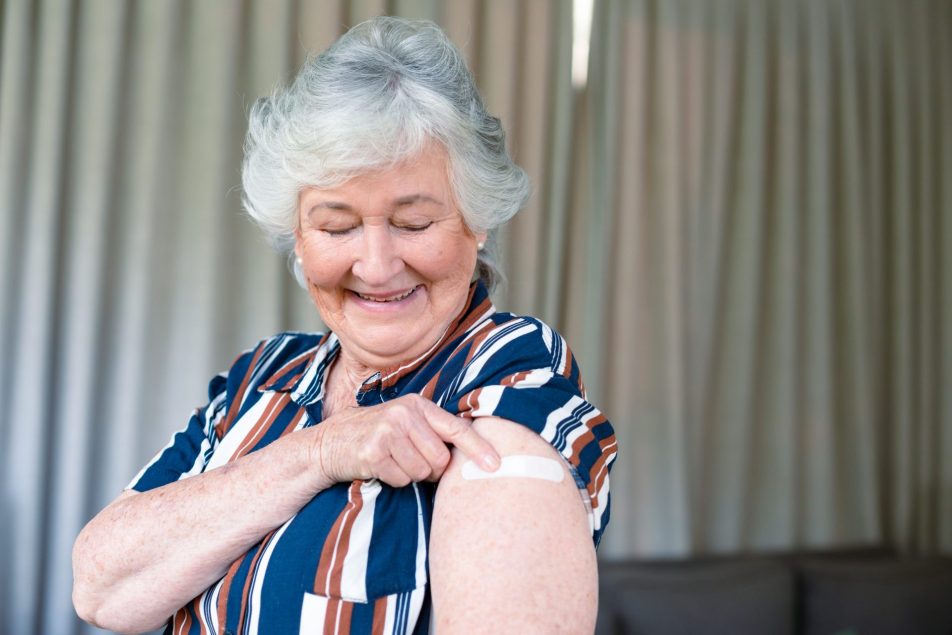 donna anziana guarda braccio con cerotto dopo vaccinazione
