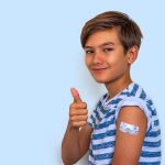 bambino fa gesto del pollice alzato con cerotto sul braccio dopo vaccinazione