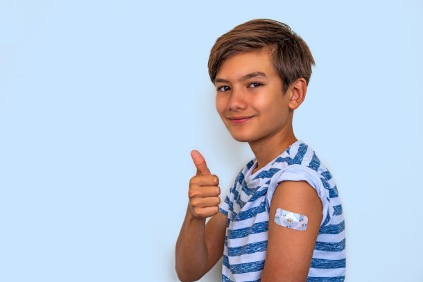 bambino fa gesto del pollice alzato con cerotto sul braccio dopo vaccinazione